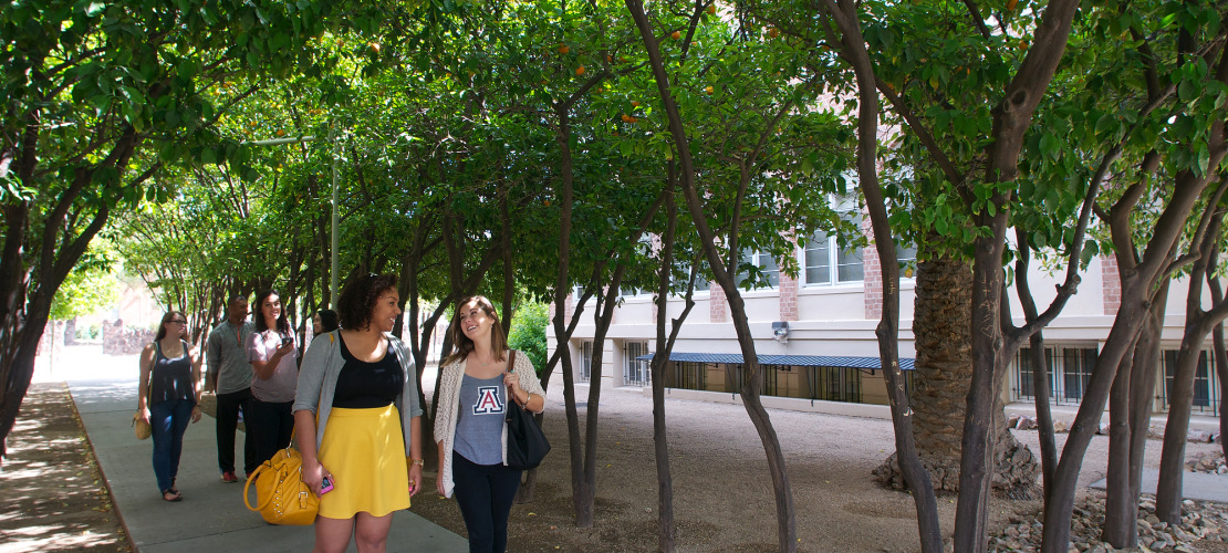 two UA students walking under trees